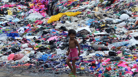 Un niño indio pasa junto  a un montón de piezas de tela en Mumbai el 15 de septiembre de 2015. AFP PHOTO / INDRANIL MUKHERJEE