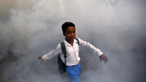 Un niño camina en medio de los gases de una fumigación realizada por un trabajador municipal en una localidad residencial en Nueva Delhi, India, 15 de septiembre de 2015. REUTERS / Anindito Mukherjee
