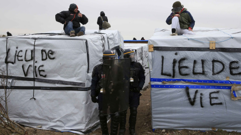 Agentes antidisturbios pasan entre los refugios levantados en la 'Jungla' de Calais. - REUTERS Agentes antidisturbios pasan entre los refugios levantados en la 'Jungla' de Calais. - REUTERS