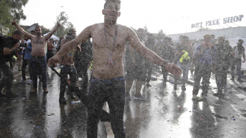 Migrantes protestan frente a los antidisturbios húngaros, que les han intentado disuadir con gas lacrimógeno y cañones de agua, cerca de Röszke. REUTERS