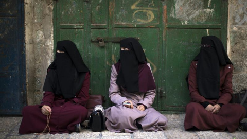 Tres activistas palestinas del grupo Murabitat (Palestinos del este de Jerusalén y Árabes israelíes) sentadas en un callejón tras ser bloqueadas por las fuerzas de seguridad israelíes. EFE/Atef Safadi