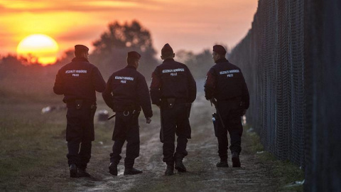 Policías húngaros patrullan al amanecer a lo largo de la valla fronteriza en Roszke (Hungría). EFE/SANDOR UJVARI