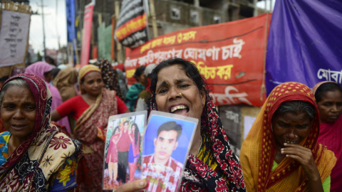 Una mujer con unas fotos de un conocido desaparecido en la tragedia de Rana Plaza. MUNIR UZ ZAMAN / AFP