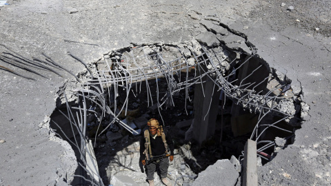 Un miembro del grupo rebelde de los hutíes mira desde un agujero en un edificio que resultó alcanzado en un nuevo ataque aéreo de la coalición liderada por Arabia Saudí en Saná (Yemen), hoy, 17 de septiembre de 2015. EFE/Yahya Arhab