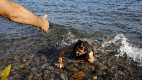 Un hombre ayuda a un refugiado sirio que nadó hasta la orilla desde el bote en la costa de Lesbos, 17 de septiembre, 2015. REUTERS/Yannis Behrakis