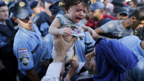 Un emigrante coge a su bebé mientras espera a subirse abordo de un bus en Tovarnik, Croacia, 17 de septiembre, 2015. REUTERS/Antonio Bronic