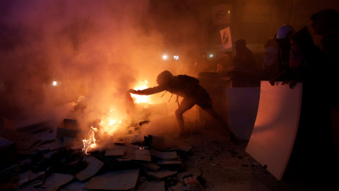 Un hombre encapuchado aviva el fuego durante las protestas en el centro de Barcelona. /REUTERS