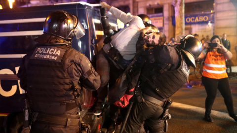 Dos mossos intentan soltar a un hombre agarrado a una furgoneta de la Policía durante las protestas que se han producido en el centro de Barcelona. /REUTERS