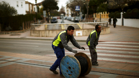 Dos trabajadores trasladan un rodillo de cable eléctrico en la localidad malagueña de Ronda. REUTERS / Jon Nazca Dos trabajadores trasladan un rodillo de cable eléctrico en la localidad malagueña de Ronda. REUTERS / Jon Nazca