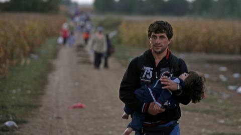 Un refugiado lleva a una niña en brazos cerca de la frontera de Croacia. REUTERS
