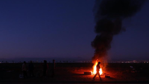 Un grupo de personas pasa la noche al aire libre entre los destrozos causados por el tsunami que arrasó Chile. EFE/Mario Ruiz