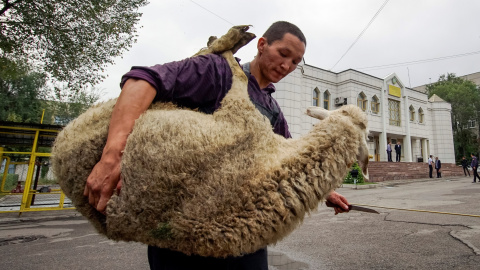 Un carnicero lleva una oveja para el sacrificio para marcar Kurban -AIT, también conocido como Eid al-Adha, en la Mezquita Central en Almaty, Kazajstán. REUTERS/Shamil Zhumatov