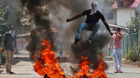 Un hombre con un pasamontañas salta por encima de una quema de desechos durante una protesta contra los recientes asesinatos en Cachemira, en Srinagar, India. REUTERS/Danish Ismail
