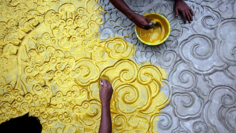 Varios artistas indios trabajan sobre un lienzo improvisado de madera, metal, bambú y papel de colores, bajo el tema "Salvad el medioambiente" del pintor y escultor Pradip Das durante los preparativos del festival Durgá Puyá en Calcuta, Ind