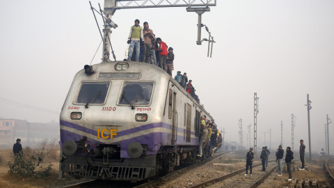 Passengers crowd atop a train as they travel on a cold winter morning at a railway station in Ghaziabad on the outskirts of New Delhi December 29, 2014. REUTERS/Anindito Mukherjee
