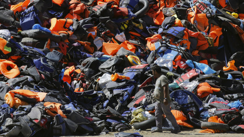 Un hombre pasa junto a una montaña de botes desinflados y chalecos salvavidas dejados por los refugiados tras su llegada a la isla griega de Lesbos. REUTERS Un hombre pasa junto a una montaña de botes desinflados y chalecos salvavidas dejados por los refugiados tras su llegada a la isla griega de Lesbos. REUTERS