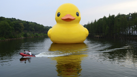 Trabajadores viajan en un barco de alta velocidad y pasan por delante de pato de goma inflable colocado por el artista holandés Florentijn Hofman, en un lago en un jardín botánico en Changsha, provincia de Hunan , China. REUTERS/Stringer