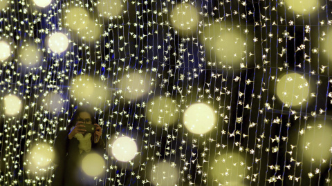 Una mujer fotografía una instalación de luces durante la presentación del NightFest en Canberra (Australia) hoy. El NighFest es parte del festival anual de flores "Floriade" que se celebra del 23 al 27 de septiembre. EFE/Lukas Coch