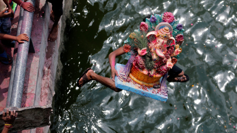 Un devoto que lleva un ídolo del dios hindú Ganesh, el dios de la prosperidad, salta al río Sabarmati para sumergir el ídolo en el último de los diez días de duración del festival de Ganesh Chaturthi en Ahmedabad, India. REUTERS/Amit Dave