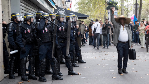 Un peatón levanta el puño a su paso delante de los policías durante una manifestación contra la nueva reforma laboral en París.- EFE/Etienne Laurent