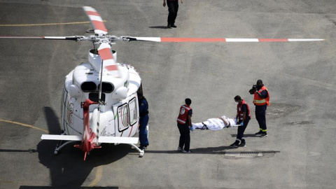 Trabajadores de la Media Luna Roja trasladan a una mujer al hospital víctima de un golpe de calor durante los rezos del mediodía a 47 grados centígrados en la mezquita de Nimra.- EFE