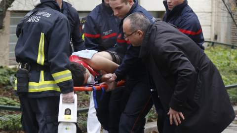 Unos bomberos trasladan en una camilla a uno de los heridos en el ataque al semanario satrico francés 'Charlie Hebdo'. REUTERS/Jacky Naegelen