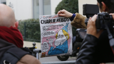 Un periodista sostiene un ejemplar de la revista 'Charlie Hebdo' con una caricatura del escritor francés Michel Houellebecq, junto al cordón policial cerca de las oficinas de la revista. REUTERS/Jacky Naegelen
