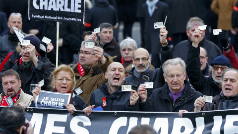 French journalists holding up their Press card take part in a hundreds of thousands of French citizens solidarity march (Marche Republicaine) in the streets of Paris January 11, 2015. French citizens will be joined by dozens of foreign lead