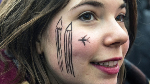 A woman wears a cartoon painting on the face during a silent protest for the victims of the shooting at the Paris offices of weekly newspaper Charlie Hebdo, at the Pariser Platz square in Berlin January 11, 2015. REUTERS/Hannibal Hanschke