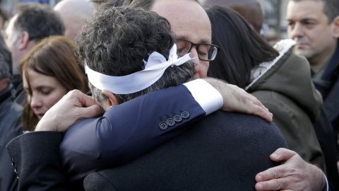 French President Francois Hollande (R) comforts French columnist for Charlie Hebdo Patrick Pelloux as they take part with family members and relatives in a solidarity march (Marche Republicaine) in the streets of Paris January 11, 2015. Hun