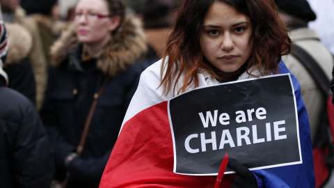 A woman wearing a French national flag holds a 'We are Charlie' sign during a march for the victims of the shootings by gunmen at the offices of the satirical weekly newspaper Charlie Hebdo in Paris, in Liverpool, northern England January 1