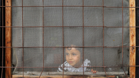 Un niño mira a través de una ventana dentro de un campo de refugiados y migrantes en el suburbio de Belgrado Krnjaca. REUTERS/Marko Djurica
