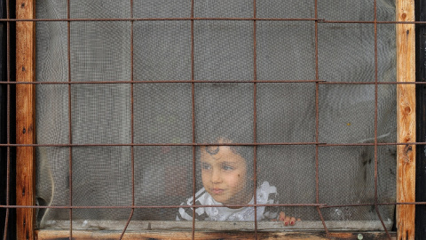 Un niño mira a través de una ventana dentro de un campo de refugiados y migrantes en el suburbio de Belgrado Krnjaca, Serbia. REUTERS / Marko Djurica