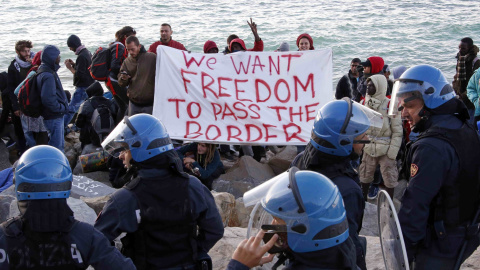 Activistas y emigrantes sostienen una pancarta que dice "Queremos libertad para cruzar la frontera" al enfrentarse con la policía italiana en el mar Mediterráneo entre Ventimiglia, Italia y Menton, Francia. REUTERS / Eric Gaillard