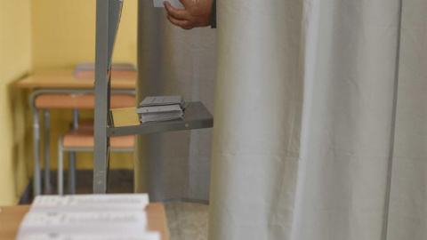 Un hombre elige la papeleta en un colegio electoral de Bilbao para depositar su voto epara las elecciones autonómicas vascas. EFE/Miguel Toña