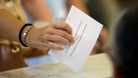 Una  mujer deposita su voto en la urna en un colegio electoral en Vigo. REUTERS/Miguel Vidal