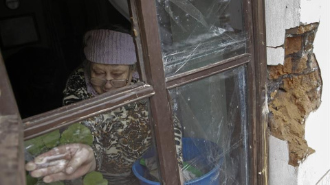 Una mujer repara con cinta adhesiva una ventana que quedó destrozada tras un bombardeo en Donetsk, Ucrania, hoy, lunes 9 de febrero de 2015. El Gobierno alemán anunció ayer la celebración de una cumbre en Minsk (Bielorrusia) este miércoles 