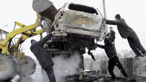 Varios operarios retiran un coche dañado tras un bombardeo en el puente Petrovskiy de Donetsk, Ucrania, el 10 de febrero del 2015. Unidades de las Guardia Nacional apoyadas por efectivos del Ejército ucraniano se han hecho con el control de