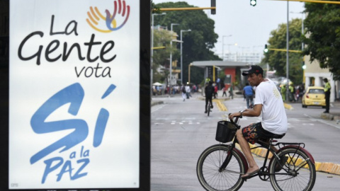 Un hombre monta en bicicleta junto a un cartel promoviendo el voto por el si al acuerdo de paz entre las FARC y el Gobierno de Colombia, en el referendum previsto para el próximo 2 de octubre. AFP / Luis Robayo