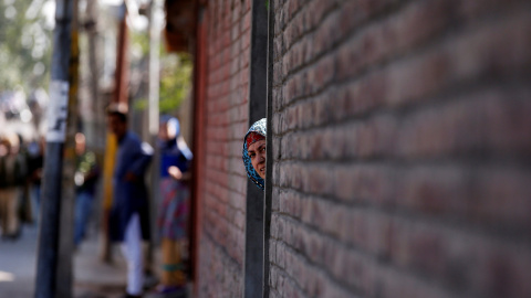 Una mujer asoma la cabeza fuera de una puerta durante una protesta en Srinagar en contra de los recientes asesinatos en la región de Cachemira, India. REUTERS/Danish Ismail