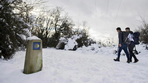 Dos peregrinos coreanos caminan por el Alto de Erro (Navarra) que esta mañana ha amanecido nevado debido al temporal de frío y nieve que azota el norte de la comunidad Foral. EFE/Villar López