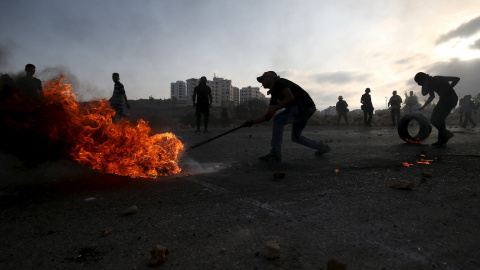 Palestinos mueven un neumático ardiendo durante enfrentamientos con el ejército israelí cerca del asentamiento judío de Bet El, cerca de la ciudad ocupada de cisjordana de Ramala, 5 de octubre de 2015. REUTERS/Mohamad Torokman
