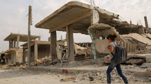 Los niños sirios caminan al lado de los escombros en su camino al colegio en el segundo día del nuevo año escolar, el 6 de octubre de 2015, en la ciudad kurda de Siria de Kobane. AFP PHOTO / delil Souleiman