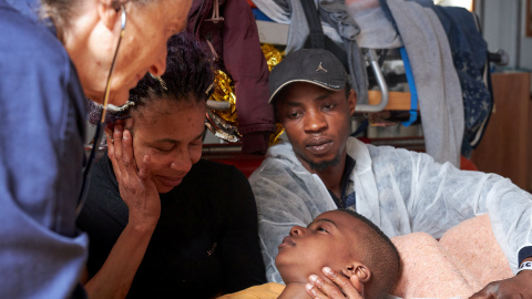 Un niño migrante yace en brazos de su madre en la sala de hospital del buque Alan Kurdi, dirigido por la organización benéfica alemana Sea-Eye, en el mar Mediterráneo. / REUTERS