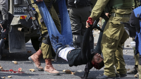Dos soldados israelíes transportan a un palestino, herido en un enfrentamiento con soldados del Ejército en el puesto militar de Beit El, cerca de Ramala, en el territorio palestino ocupado de Cisjordania, Palestina. EFE/Str