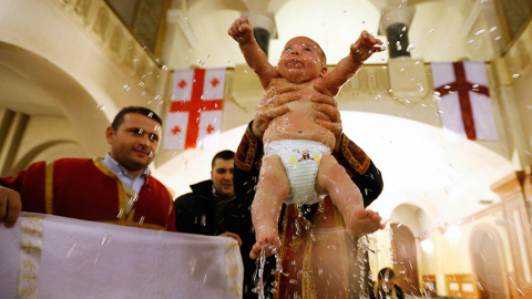Un bebé es bautizado durante una ceremonia de bautismo en masa en el día de la Epifanía en Tbilisi. /DAVID MDZINARISHVILI (REUTERS)