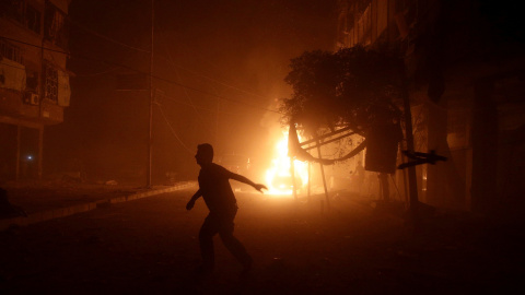 Un hombre corre lejos de un coche en llamas después de un ataque aéreo en el barrio rebelde de Douma, en Damasco, Siria. REUTERS / Bassam Khabieh