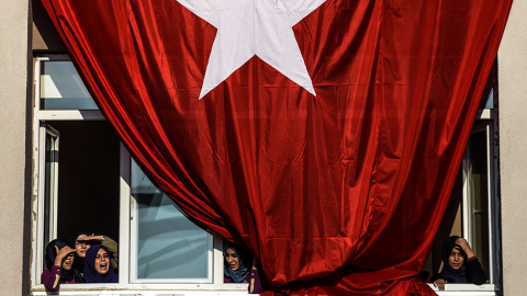 Estudiantes junto a una bandera turca gigante mientras esperan el discurso del primer ministro Ahmet Davutoglu.- OZAN KOSE (AFP