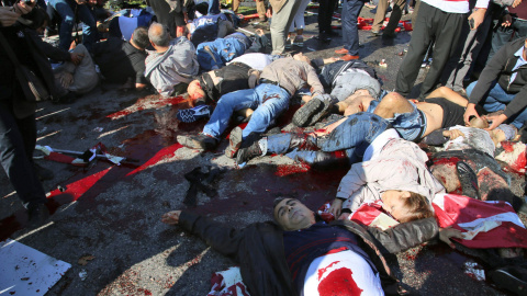 Las víctimas mortales de los antentados en el centro de Ankara yacen en el suelo mientras algunas personas tratan de auxiliar a los heridos. EFE/EPA/STR