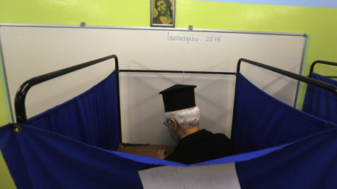 Un sacerdote ortodoxo griego dentro de una cabina electoral. REUTERS/Yannis Behrakis